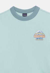 Φωτεινό γαλάζιο T-shirt Patagonia με σκούρο μπλε γιακά και μικρό λογότυπο με κύμα, βουνό και κείμενο "Great Pacific Iron Works."