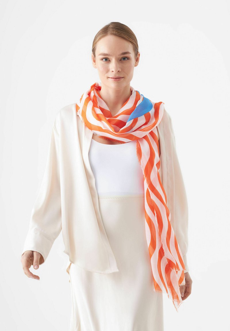 Écharpe légère avec de larges rayures orange et blanches, accentuées de bleu, fabriquée dans un tissu doux, se drape avec élégance autour du cou.