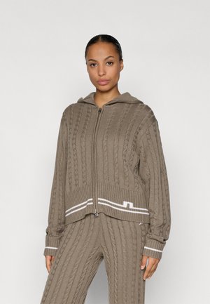 Brown cable knit hoodie with white stripe detail on hem and cuffs; features a zip closure and a hood. Paired with matching cable knit pants.