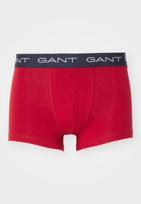 Boxers rojos fabricados en algodón suave. Cuentan con una cinturilla azul marino con el logotipo en blanco "GANT". Diseño simple sin patrones adicionales.