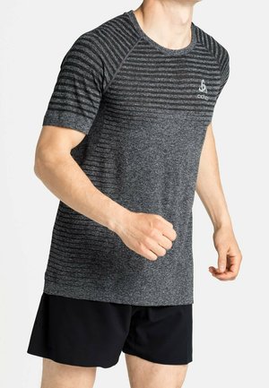 Mężczyzna w szarym, sportowym koszulce z krótkim rękawem z wzorem i czarnych szortach, w pozycji do biegu na białym tle.