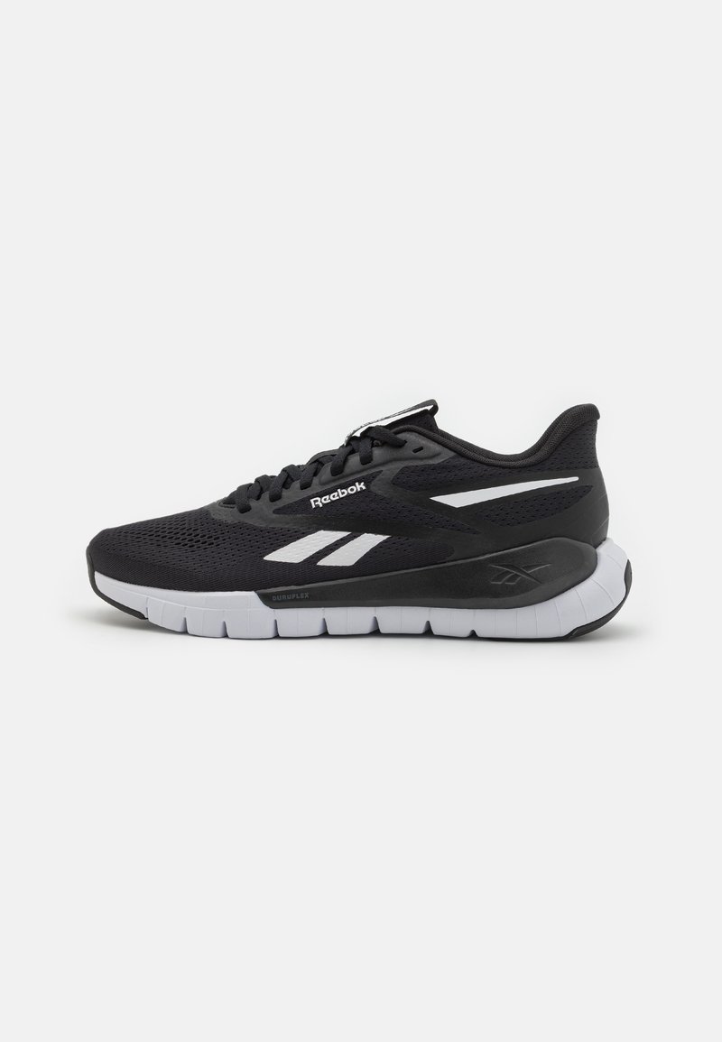 Čierna športová topánka s sieťovaným zvrškom, bielymi detailami a polstrovanou podrážkou. Obsahuje logo Reebok a má štíhly, priedušný dizajn.