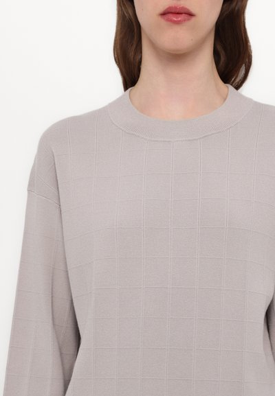 Pulover tricotat de culoare gri deschis, cu un model texturat în forme pătrate, guler rotund și mâneci lungi, lejere.