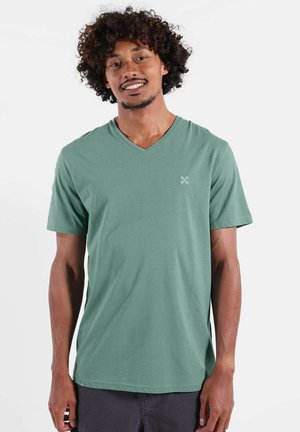T-shirt col en V en tissu vert doux, avec des manches courtes et un petit logo sur la poitrine gauche. Coupe régulière avec une texture lisse.