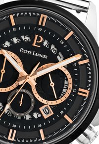 Svart och guld kronograf klocka med ett runt metallhölje, lysande visare och texturerad svart urtavla med arabiska siffror och flera sub-dialer.