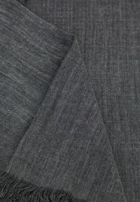 Écharpe grise texturée avec des rayures verticales subtiles. Tissu doux avec des bords frangés, pliée pour mettre en valeur sa légèreté et sa surface lisse.