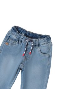 Pantaloni in denim azzurro chiaro con cintura elastica, dotati di un cordino a righe bianco e nere con dettagli rossi e tasche frontali.