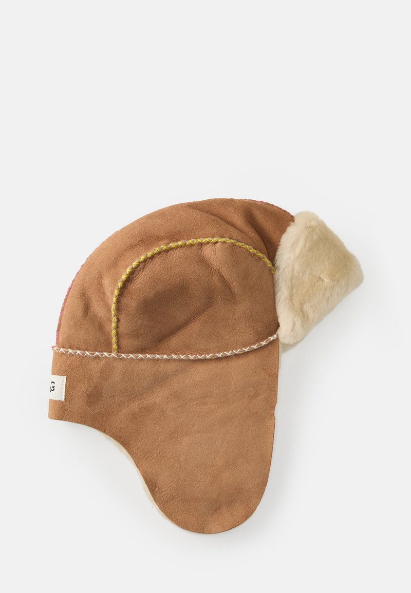 Ruskohi aviator-tyylinen ruskea nahkahatun, jossa on vaaleanbeige turkisreunus, keltaista ja vaaleanpunaista ommeltua yksityiskohtaa sekä korvaläpät lisälämpöä varten.