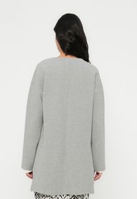 Γκρι φούτερ με υφασμάτινη υφή, φαρδιά μανίκια και ευθεία πίσω όψη. Διαθέτει στρογγυλή λαιμόκοψη και απλό σχέδιο.