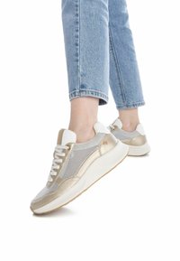 Zapatillas de malla blancas y doradas con acentos texturizados, puntera redondeada y suela acolchada. Los cordones son blancos; la parte trasera presenta un detalle de logo.