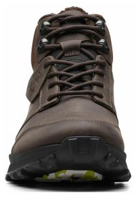 Scarponcino da trekking marrone con tomaia in pelle testurizzata, pannelli in rete nera e suola robusta. Presenta una ferramenta per i lacci in metallo e un dettaglio con logo.