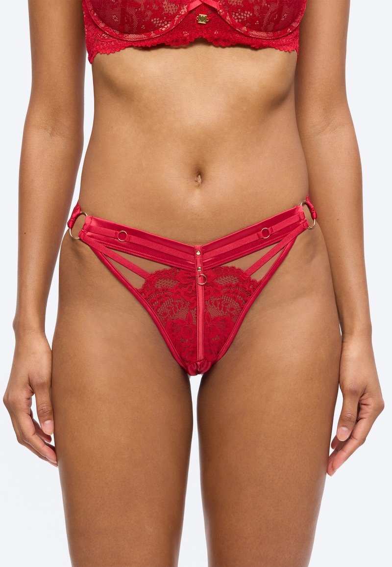 Γυναικείο μέσο τμήμα φορούν κόκκινο δαντελένιο σουτιέν και αντίστοιχο δαντελένιο εσώρουχο με λουράκια και μεταλλικά δαχτυλίδια στους γοφούς και στο κέντρο μπροστά.