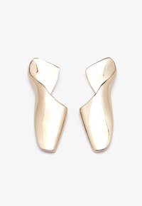 Orecchini in tonalità oro con una forma scultorea attorcigliata e una superficie liscia e riflettente. Design minimalista senza chiusure visibili.