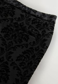 Tissue de catifea neagră cu un model damascat texturat. Include o buzunar lateral și margini netede.