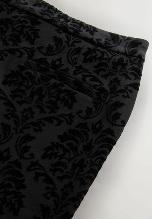 Svart sammetstyg med en texturerad damaskmönster. Inkluderar en sidficka och släta kanter.