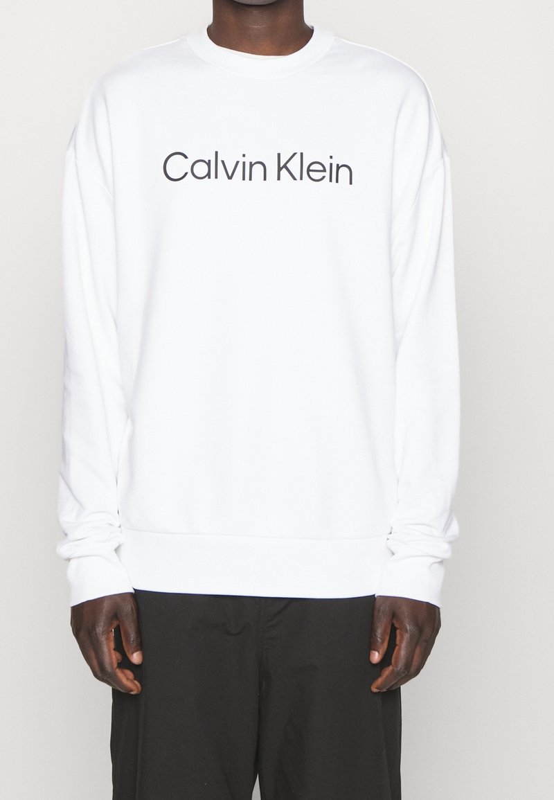 Witte sweatshirt met het "Calvin Klein" logo in een vet, donker lettertype. Ribgebreide manchetten en zoom met een losse pasvorm. Zachte stoftextuur.
