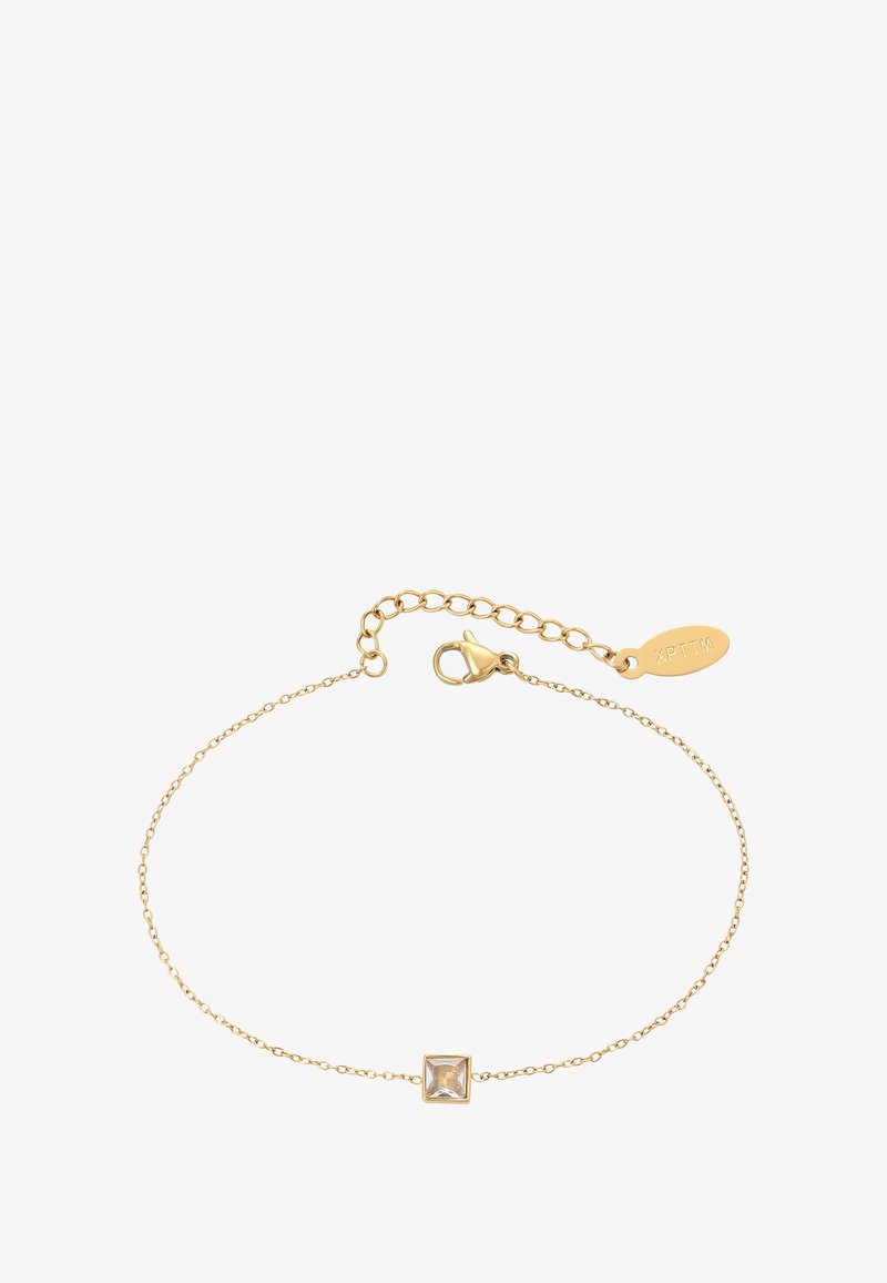 Jemný zlatý řetízek na zápěstí s čtvercovým čirým drahokamem jako středem a nastavitelným zapínáním s malou vyrytou značkou.