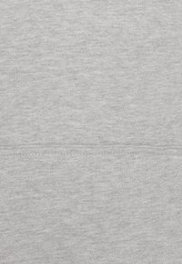 Tissu gris clair avec une couture horizontale et un motif tricoté texturé visible.