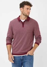 Polo a maniche lunghe bordeaux con finitura testurizzata, abbottonatura e taschino sul petto. Collo e polsini a contrasto.