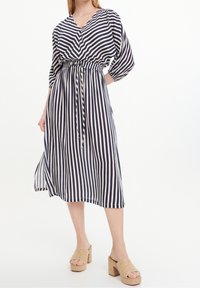 Gestreiftes Kleid in Navy und Weiß, mit V-Ausschnitt, tailliertem Gürtel und dreiviertelärmeln; aus leichtem Stoff mit fließender Silhouette.