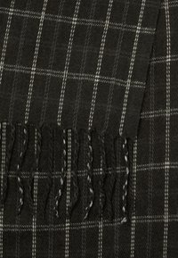 Écharpe à carreaux sombre en tissu texturé, avec des lignes blanches et gris clair, et des bords frangés pour un détail supplémentaire.