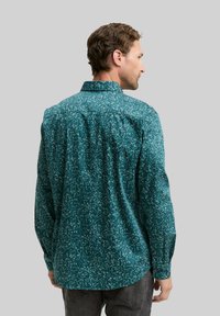 Teal overhemd met knopen en een bloemenpatroon. Zacht stof, lange mouwen en een rugpand detail. Beschikt over een ronde zoom en knopenmanchetten.