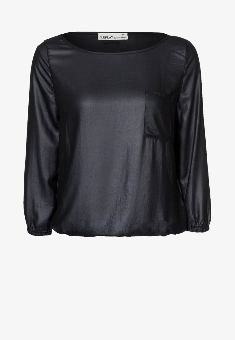 Blouse noire à manches longues avec un col rond, des poignets et un ourlet élastiques, et une petite poche sur le côté gauche de la poitrine.