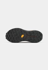 Semelle en caoutchouc noir avec un motif de crampons agressif, arborant un logo Vibram jaune, conçu pour l'adhérence et la traction sur des surfaces variées.