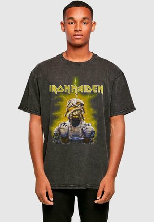 Black cotton oversized T-shirt featuring a graphic print of a character with chains, lightning, and the text "IRON MAIDEN" in yellow.