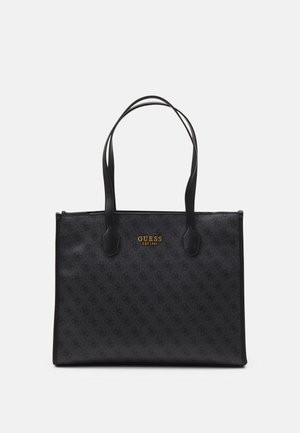 Sort Guess shopper-taske med dobbelte håndtag, subtilt monogrammønster og guld "GUESS EST 1981" logo centreret på forsiden.