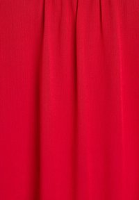 Roter Stoff mit glatter Textur, vertikalen Falten und subtiler Glanz, geeignet für Bekleidungs- oder Wohnaccessoires.