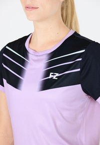Lys lilla atletisk skjorte med sorte og lyseblå diagonale striber på den øverste del, med et lille hvidt "FZ" logo. Glat tekstur.