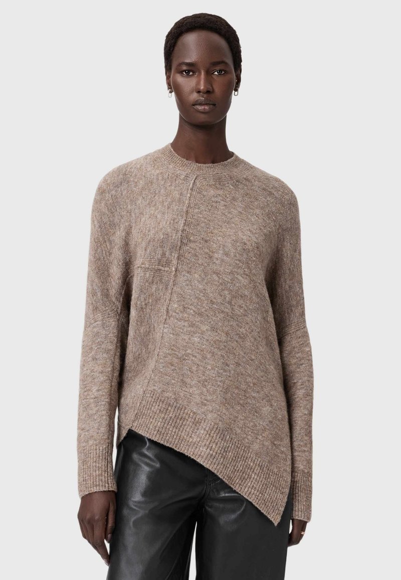 Maglione marrone a maglia con finitura testurizzata, orlo asimmetrico e polsini a coste. Abbinato a pantaloni in pelle neri per un contrasto.