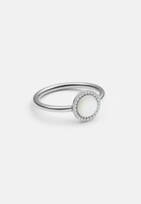 Anello d'argento con una pietra ovale bianca, circondata da una cornice circolare di piccole gemme trasparenti, con una fascia sottile e liscia.