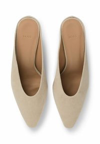 Beige suede mules with pointed toes, open back, and smooth interior. The brand logo "BOSS" is subtly embossed on the heel.