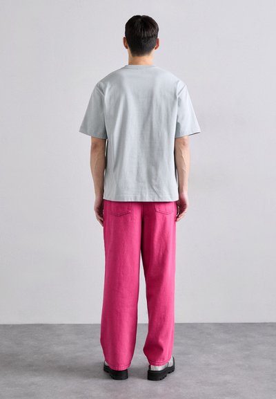 Γκρι βαμβακερό μπλουζάκι με κοντά μανίκια, συνδυασμένο με φαρδιά ροζ παντελόνια και μαύρες πλατφόρμες. Απλός, καθημερινός σχεδιασμός.