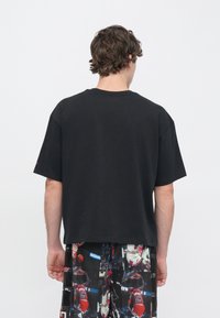 Μαύρο κοντομάνικο μπλουζάκι με στρογγυλή λαιμόκοψη, με άνετη εφαρμογή και μαλακό βαμβακερό υλικό. Χωρίς ορατά λογότυπα ή σχέδια.