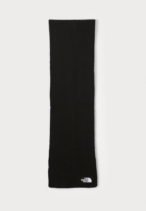 Écharpe en tricot noire avec une texture ribbed aux extrémités. Présente une petite étiquette de logo blanche. Forme longue et rectangulaire pour un port polyvalent.