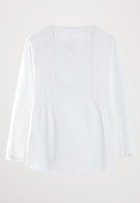 Valkoinen pitkähihaisen paita, jossa on pyöristetty helma, pleatattu selkä ja napilliset hihansuut. Valmistettu kevyestä kankaasta, jossa on näkyviä ompelutietoja.