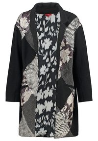 Gilet noir à motifs avec des dessins floraux et géométriques. Il présente un col à revers et une ouverture sur le devant, mettant en avant des textures contrastées.
