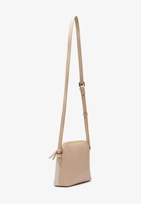 Beżowa torebka na ramię z gładkiej skóry, z regulowanym paskiem i akcentem o splatanej fakturze z jednej strony. Zapięcie na suwak.