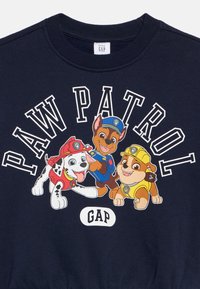 Marineblauwe sweatshirt met de tekst "PAW PATROL" en drie cartoonhonden: een Dalmatier en twee bruine honden in verschillende outfits.