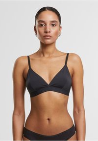 Črn trikotni bralette iz gladkega materiala, z tankimi naramnicami, V-izrezom in brezšivno zasnovo. Brez vidnih kovinskih delov ali vzorcev.
