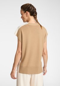 Suéter de punto de manga corta en color beige, con dobladillo acanalado y textura suave. La vista trasera muestra un diseño en bloques de color con acentos más claros.