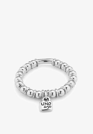 Bracelet élastique de couleur argentée avec des perles rondes et une petite plaque gravée "UNO de 50". Finition lisse et brillante avec un design uniforme.