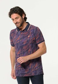 Polo shirt in paars met een bladpatroon in rood en oranje, voorzien van een zwarte kraag met contrasterende bies en een drieknoopsluiting.