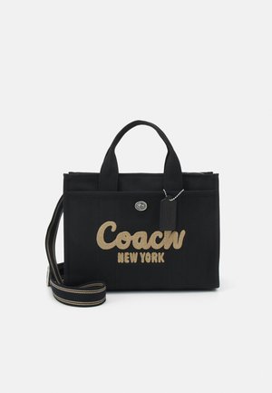Czarna torba na ramię z płótna z złotym haftowanym logo "Coach New York", górnymi uchwytami, odpinanym paskiem oraz detalami w kolorze srebrnym.