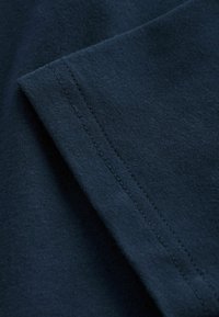 Marineblaues Baumwollgewebe mit glatter Textur, das eine klare Kante und sichtbare Nahtdetails aufweist. Weiches und leichtes Material.