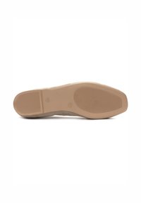 Suela de zapato de ante beige con goma texturizada para el agarre, forma redondeada y un detalle de marca mínimo. Superficie lisa con un ligero brillo.