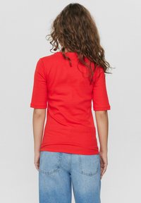 Rode getailleerde T-shirt met korte mouwen, gladde textuur, ronde hals, gecombineerd met lichtblauwe spijkerbroek met achterzakken en een relaxte pasvorm.